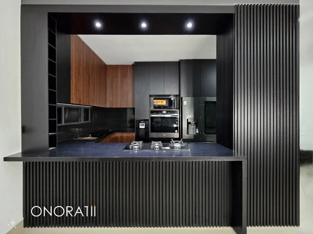 Se muestra lo que es cocinas con lambrin, este es de color oscuro, pero se ve que es de un material de madera, los gabinetes también son de madera, pero color café, por atrás se nota que hay mas accesorios que complementan a la cocina, hay un horno y la lado un refrigerador, todos los elementos que componen a la cocina estan en armonía
